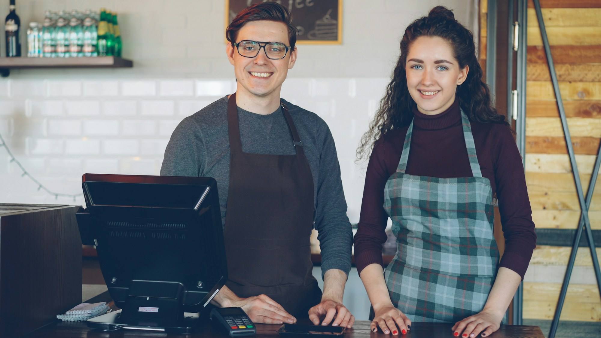 Two cafe owners behind their counter and till
