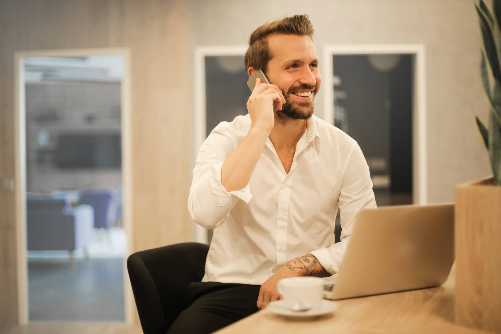 A man on the phone at his desk, smiling